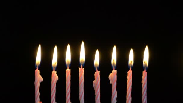 Filmmaterial bunte brennende Kerzen auf schwarzem Hintergrund. 4k — Stockvideo