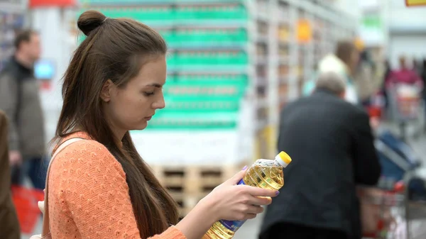 Женщина покупает подсолнечное масло в магазине — стоковое фото