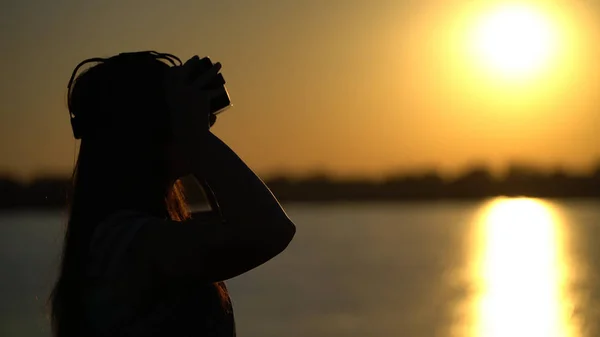Mulher em óculos de realidade virtual no fundo do pôr do sol . — Fotografia de Stock