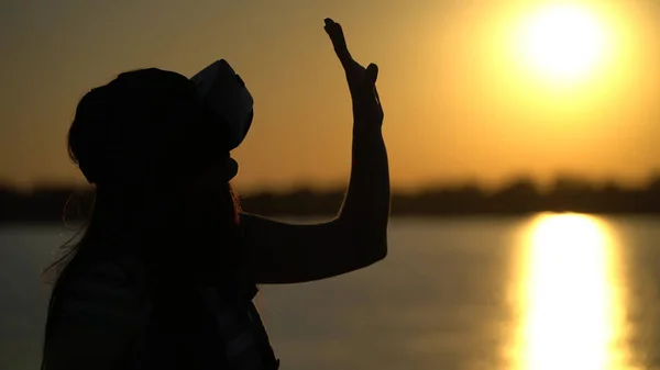 Mulher em óculos de realidade virtual no fundo do pôr do sol . — Fotografia de Stock