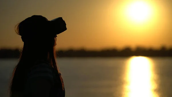 Mulher em óculos de realidade virtual no fundo do pôr do sol . — Fotografia de Stock