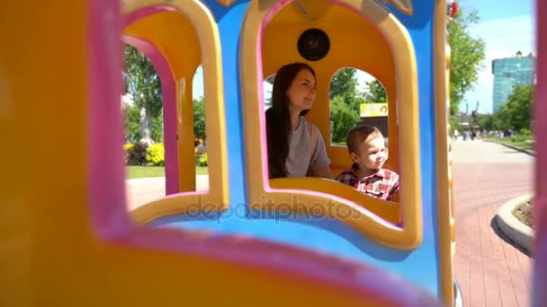 Hijo con mamá montando un tren de niños . — Vídeos de Stock