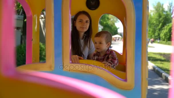 Hijo con mamá montando un tren de niños . — Vídeos de Stock