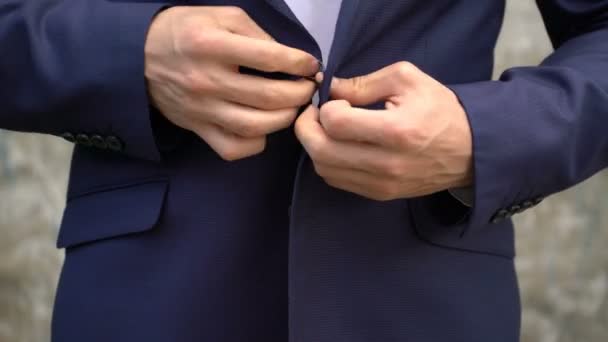 The man fastens buttons on his jacket close up. — Stock Video