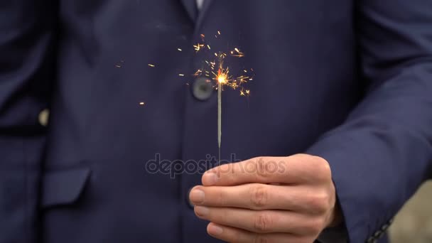 Jovem empresário de terno azul segura um fogo de bengala em sua mão . — Vídeo de Stock
