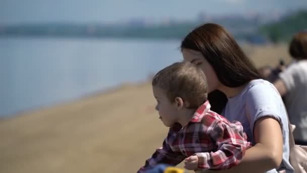 Mamá y su hijo mirando hacia adelante en el paseo marítimo . — Vídeos de Stock