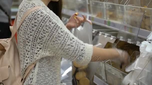 Jonge vrouw kiest cookies in een supermarkt. — Stockvideo