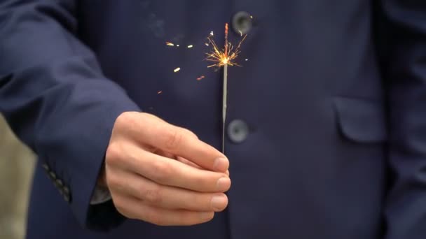 Joven hombre de negocios en traje azul sostiene un fuego de bengala en su mano . — Vídeos de Stock