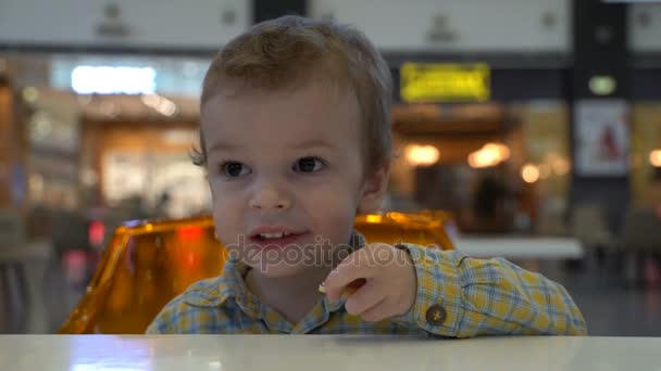 Niño comiendo papas fritas en el patio de comidas . — Vídeos de Stock