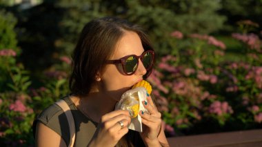 Kız açık havada haşlanmış mısır yiyor