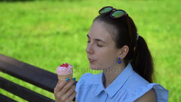 Mädchen isst Eis auf einer Parkbank. — Stockvideo