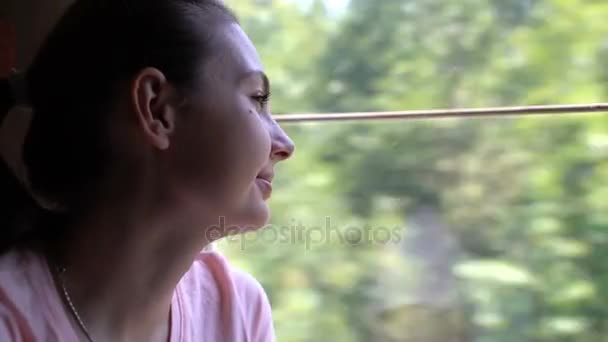 Una mujer monta en un tren y mira por la ventana . — Vídeo de stock