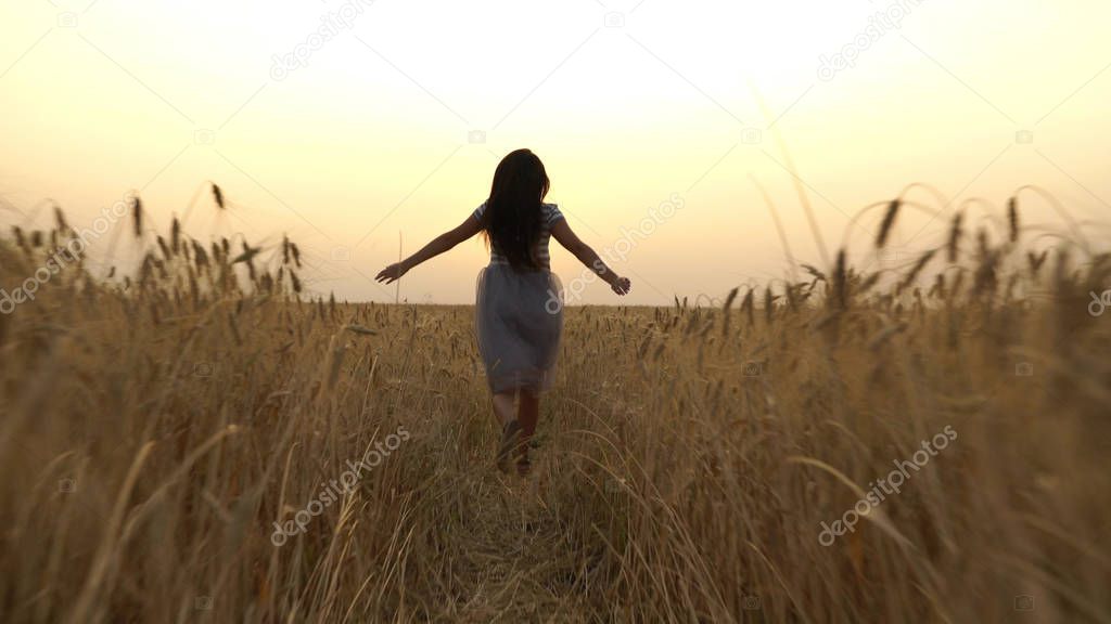 pretty girl in the dress is running across the field.