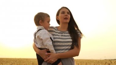 Anne ve oğlu buğday sahada günbatımında yürüyüş