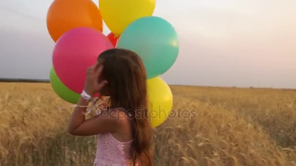 Девушка ходит по полю с воздушными шарами — стоковое видео