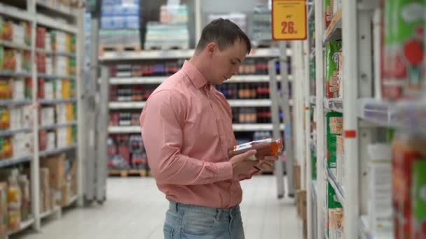 Ο νεαρός άντρας αγοράζει χυμό σε ένα κατάστημα ή σούπερ μάρκετ. — Αρχείο Βίντεο