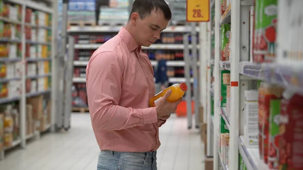 Молодой парень покупает сок в магазине или супермаркете . — стоковое фото