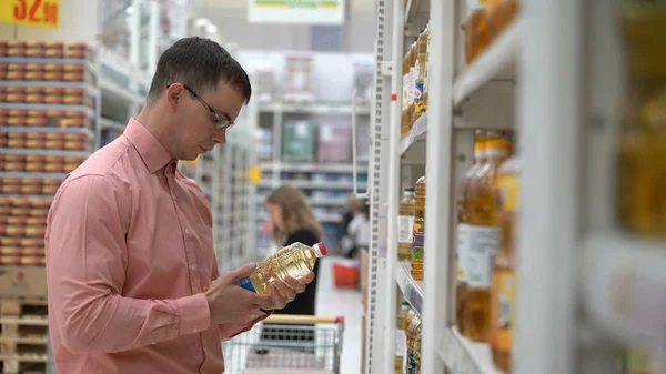 Chico joven elige un aceite de girasol en una tienda o supermercado . — Foto de Stock