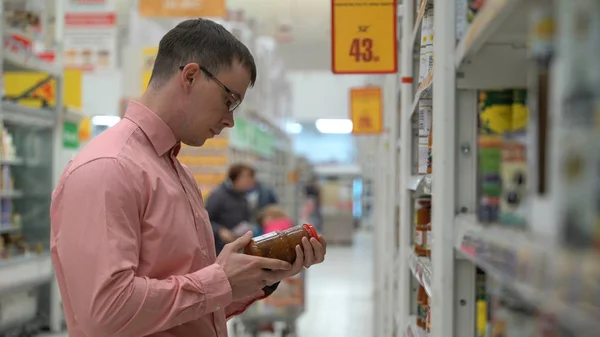 young guy chooses a pickled vegetables in a store or supermarket.