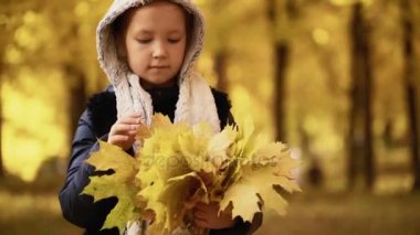 Kız yedi yıl sonbaharda bir parkta yürüyor ve yaprakları onun elinde tutan