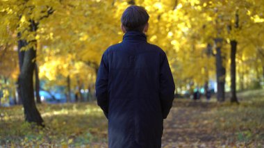 sonbahar parkta siyah montlu genç adam.