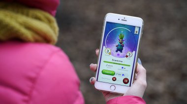 Samara, Rusya Federasyonu - 28 Kasım 2017: kadın oynarken draconius onun iphone gidin. draconius Artırılmış gerçeklik unsurları ile çok oyunculu oyun gitmek