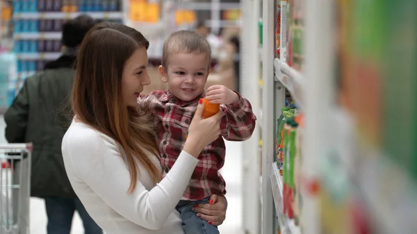Young mother and son buy water or juice in a store. — Stock Photo, Image