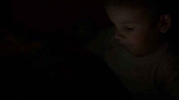 Zweijähriger Junge schaut nachts Cartoons auf seinem Tablet. — Stockvideo