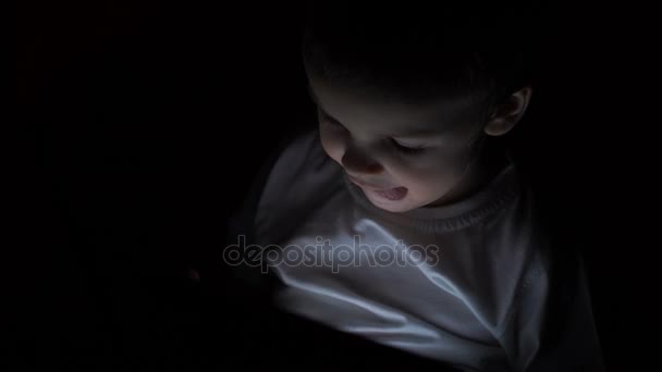 Αγόρι δύο ετών παρακολουθούν κινούμενα σχέδια στην ταμπλέτα του τη νύχτα. — Αρχείο Βίντεο