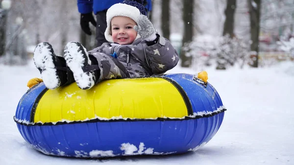 Pojke på två år rullande på slangen i parken på vintern. — Stockfoto