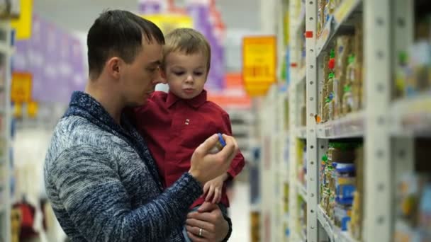 El padre y el hijo compran comida para bebés en el supermercado — Vídeo de stock