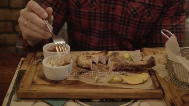 Guy is het eten van varkensvlees lendenen in een restaurant. — Stockvideo