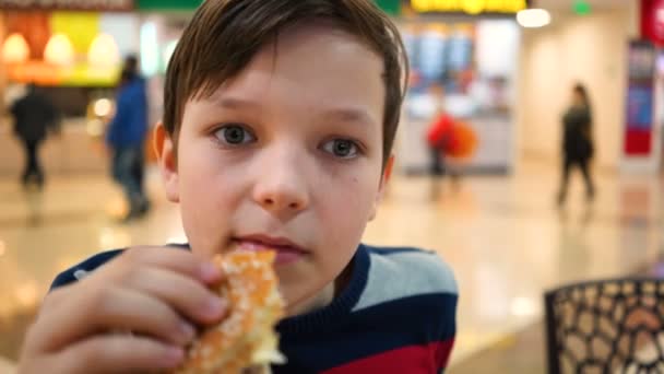 Мальчик ест бургер вблизи. . — стоковое видео