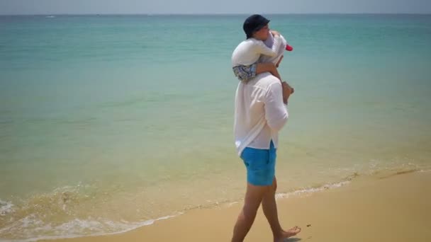 Pai e filho caminhando a pé ao longo da praia perto do oceano . — Vídeo de Stock