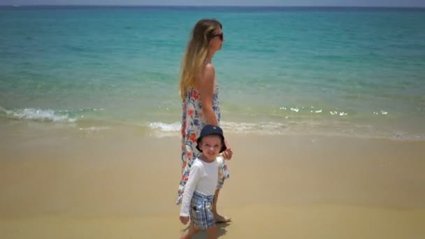 Madre e hijo caminando a pie por la playa cerca del océano . — Vídeo de stock