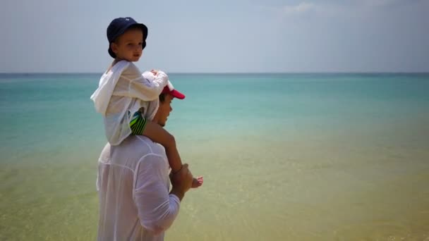 Padre e hijo caminando a pie por la playa cerca del océano . — Vídeo de stock