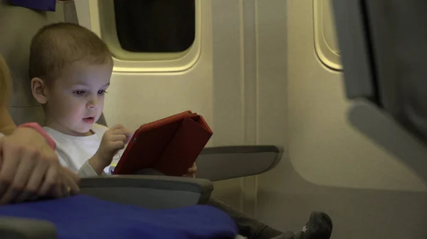 boy two years old playing on a tablet app, and sit in the aircraft seat.