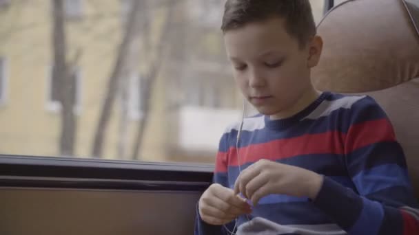 Zbliże młodego chłopca autobusem przez miasto, przy użyciu sieci społecznych na jego komputerze typu tablet. — Wideo stockowe