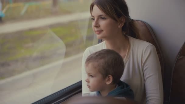 Junge Mutter und kleiner Sohn fahren bei sonnigem Wetter im Bus durch die Stadt. — Stockvideo