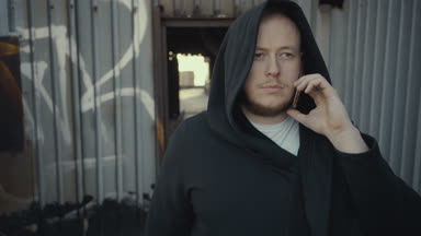 hipster adam terk edilmiş bir binada etrafında yürür ve telefonda konuşuyor.