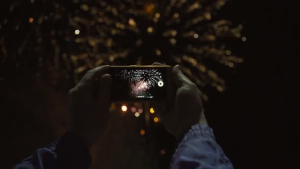 Silueta unui bărbat care fotografiază focuri de artificii pe cerul nopţii. Salut frumos în onoarea sărbătorii . — Videoclip de stoc