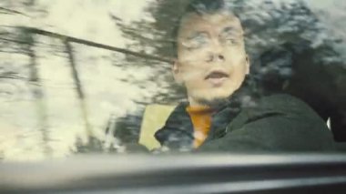 Man rides a car on the Country road. Trees reflected in car window