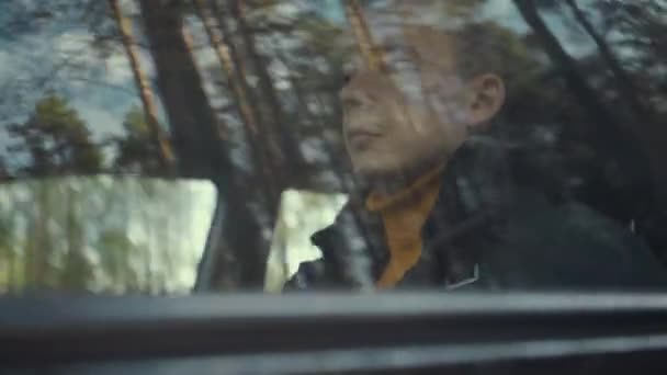 El hombre monta un coche en la carretera del campo. Árboles reflejados en la ventana del coche — Vídeos de Stock