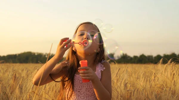 Menina caminha no campo e sopra bolhas . — Fotografia de Stock