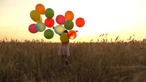 Menina andando em um campo com balões — Fotografia de Stock