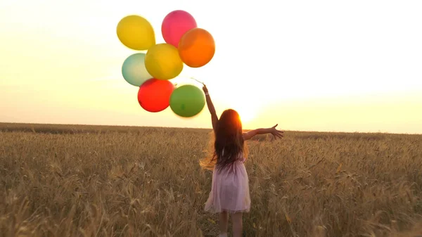 Mädchen läuft mit Luftballons auf einem Feld — Stockfoto
