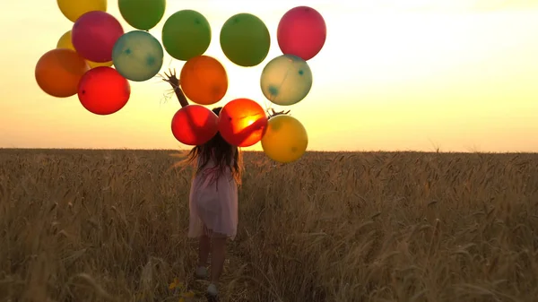 Mädchen läuft mit Luftballons auf einem Feld — Stockfoto