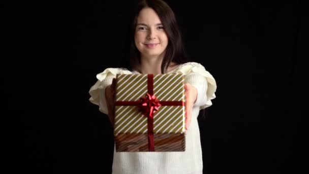 Giovane donna dà una scatola regalo su sfondo nero. confezione regalo con nastro bianco per Felice Anno Nuovo, Buon Natale, San Valentino, compleanno . — Video Stock