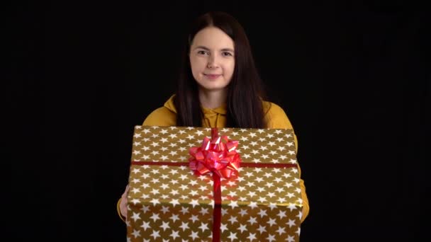 Jovem mulher dá uma caixa de presente no fundo preto. caixa de presente com fita branca para Feliz Ano Novo, Feliz Natal, Dia dos Namorados, aniversário . — Vídeo de Stock