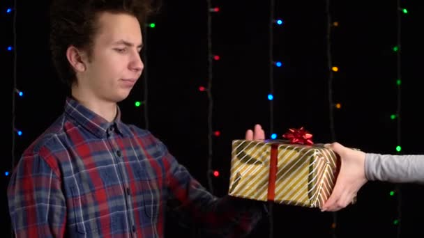 Egy fekete hátterű ajándékdobozos fiú. ajándék doboz szalaggal Boldog új évet, Boldog karácsonyt, Valentin-napot, születésnapot — Stock videók